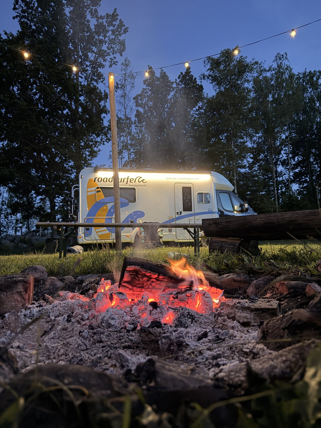 Lagerfeuer am Abend mit Glut und Lichterkette