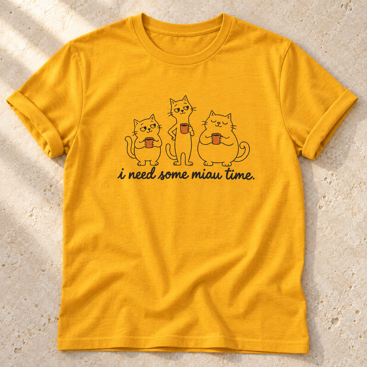 I Need Some Miau Time – Unisex Katzen-T-Shirt in Gold – natürliches Flatlay mit aufgekrempelten Ärmeln