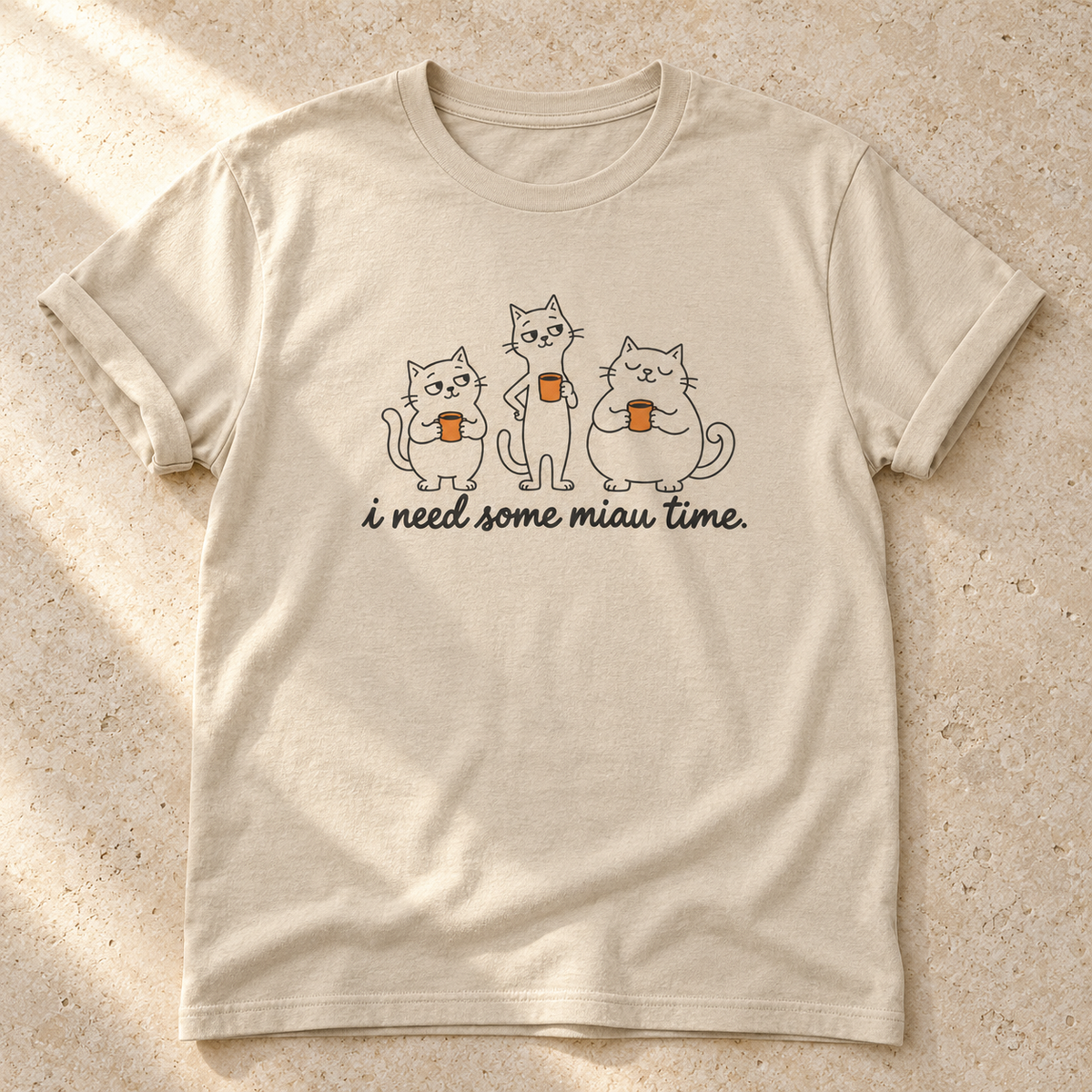 I Need Some Miau Time – Unisex Katzen-T-Shirt in Sand – natürliches Flatlay mit aufgekrempelten Ärmeln