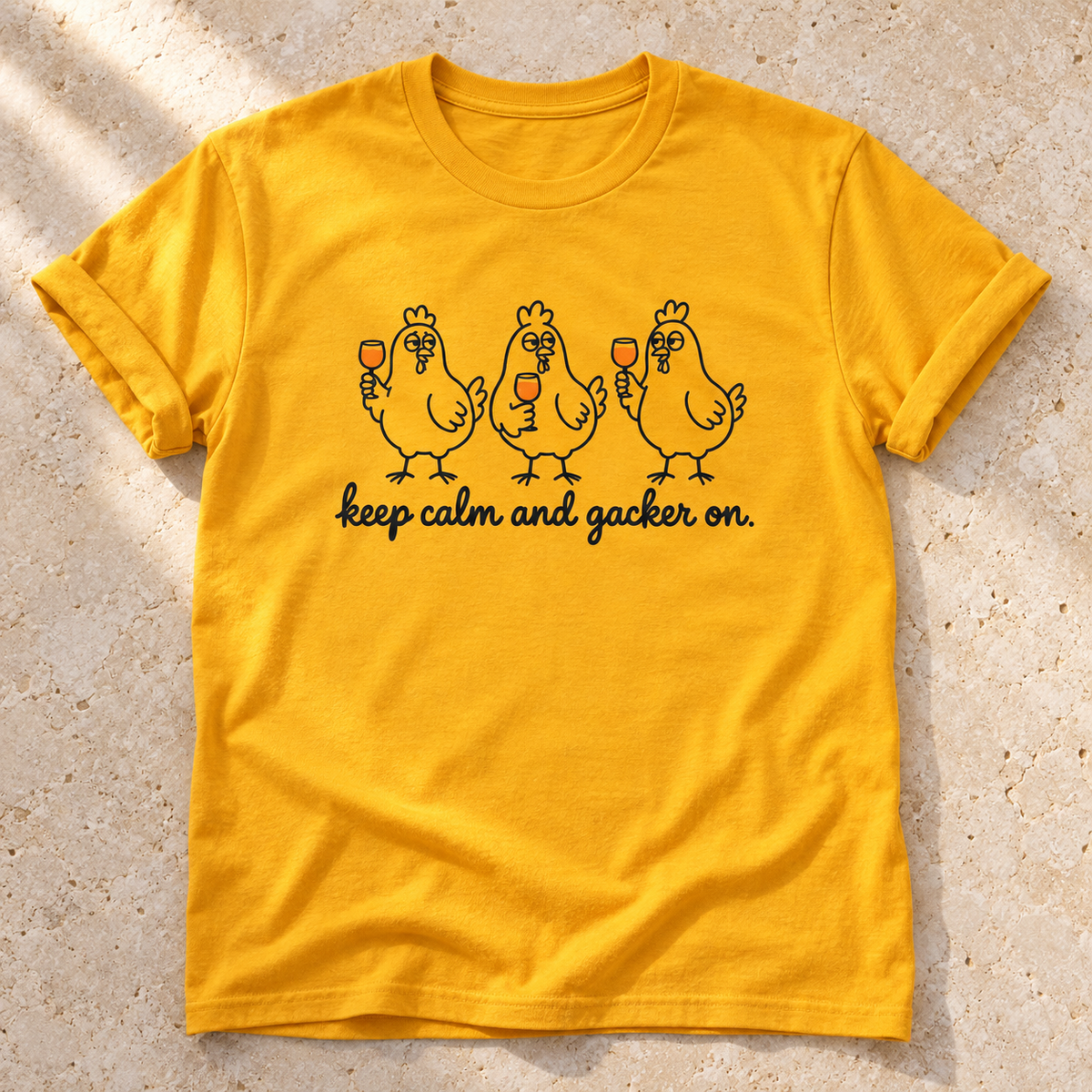 Keep Calm and Gacker On – Unisex Hühner-T-Shirt in Gold – natürliches Flatlay mit aufgekrempelten Ärmeln