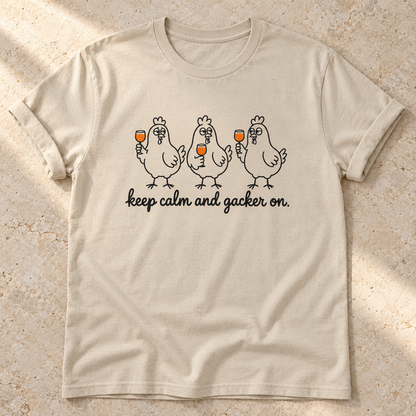 Keep Calm and Gacker On – Unisex Hühner-T-Shirt in Sand – natürliches Flatlay mit aufgekrempelten Ärmeln